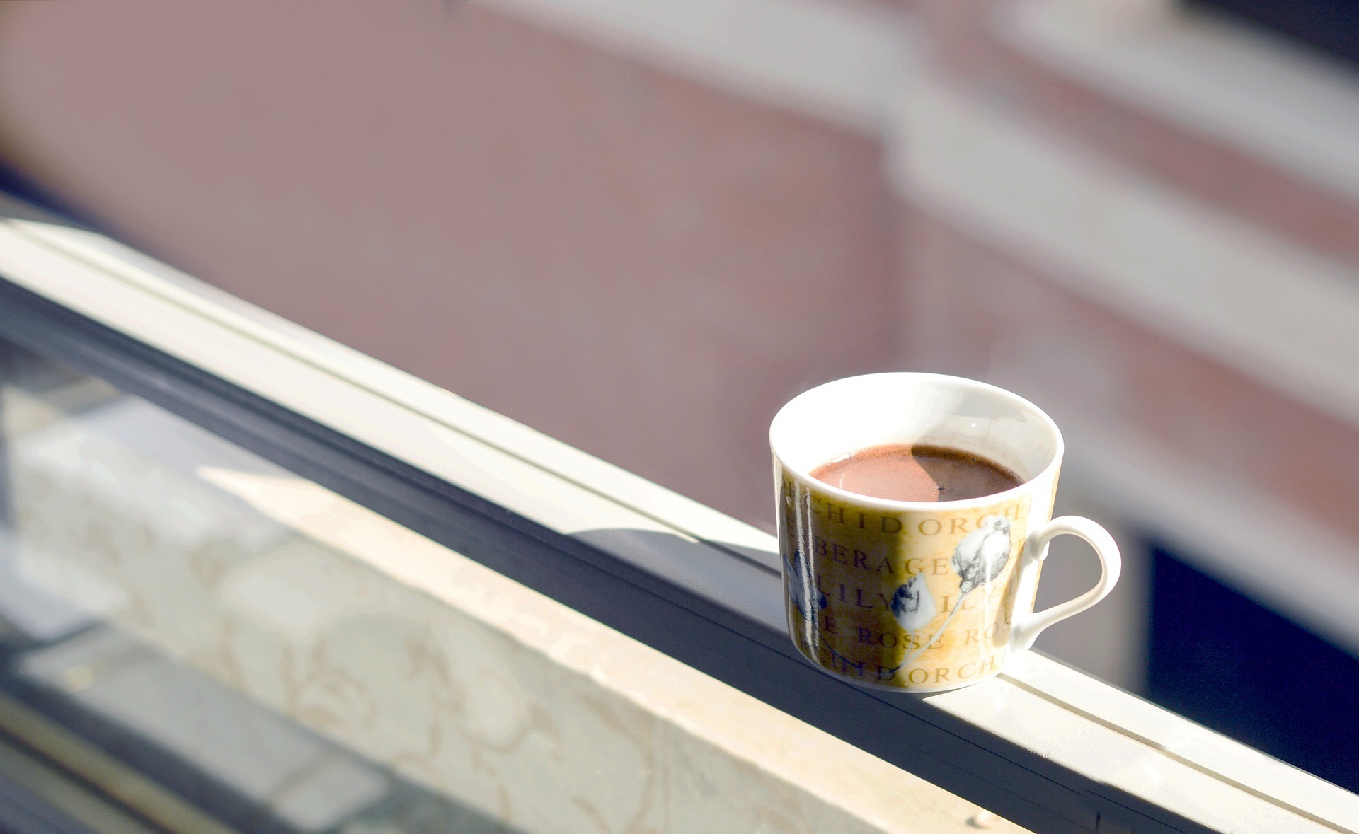 Ceramic cup of hot chocolate sitting on a window ledge